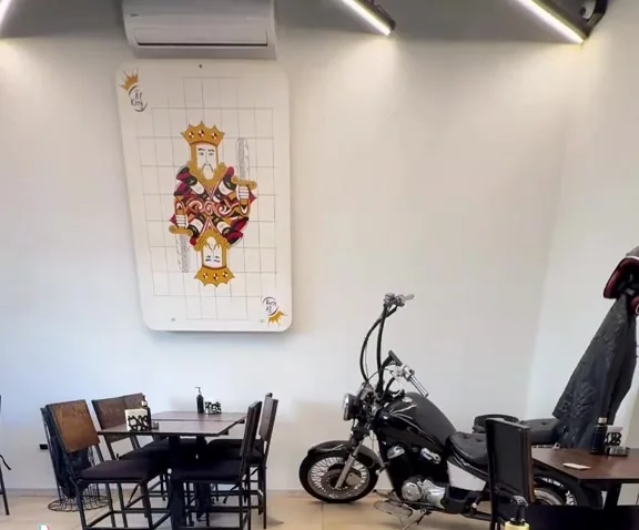Inside El King: wooden tables, a giant king playing card on the wall and a motorcycle parked in the dining room